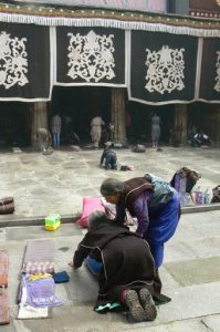 Tibet: Lhasa Women praying at entry to Jokhang.  (An elderly pilgrim