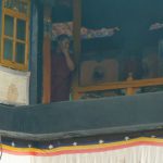 Tibet: Lhasa Monk watching the crowds of visitors to Jokhang.