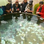 Tibet: Lhasa Chinese visitors putting money in a large water vessel