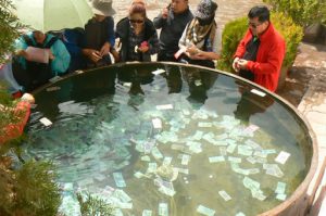 Tibet: Lhasa Chinese visitors putting money in a large water vessel