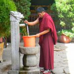 Tibet: Lhasa Young monk drawing well water at Jokhang Temple.