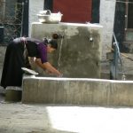 Tibet: Lhasa A woman draws water for washing from a  common