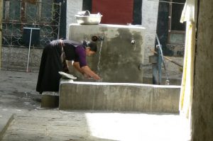 Tibet: Lhasa A woman draws water for washing from a  common