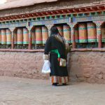 Tibet - pilgrim turns prayer wheels at Sakya Monastery.