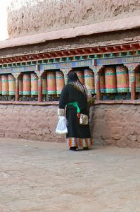 Tibet - pilgrim turns prayer wheels at Sakya Monastery.