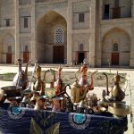 Uzbekistan: Bukhara metalware for sale in front of a madrassa (former school)