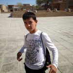 Uzbekistan: Khiva Young student showing off his shirt.