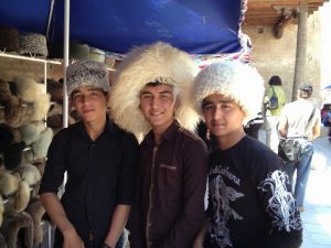 Uzbekistan: Khiva Three young men trying on souvenir hats.