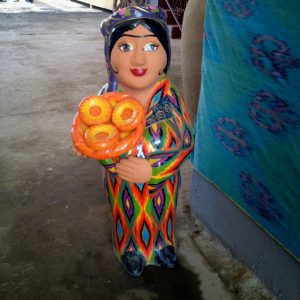 Uzbekistan: Fergana Valley, Rishton Rustam Usmanov pottery playful figure holding 'non' rounds