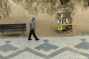 Portugal, Estremoz: patterned walkway with lone retiree
